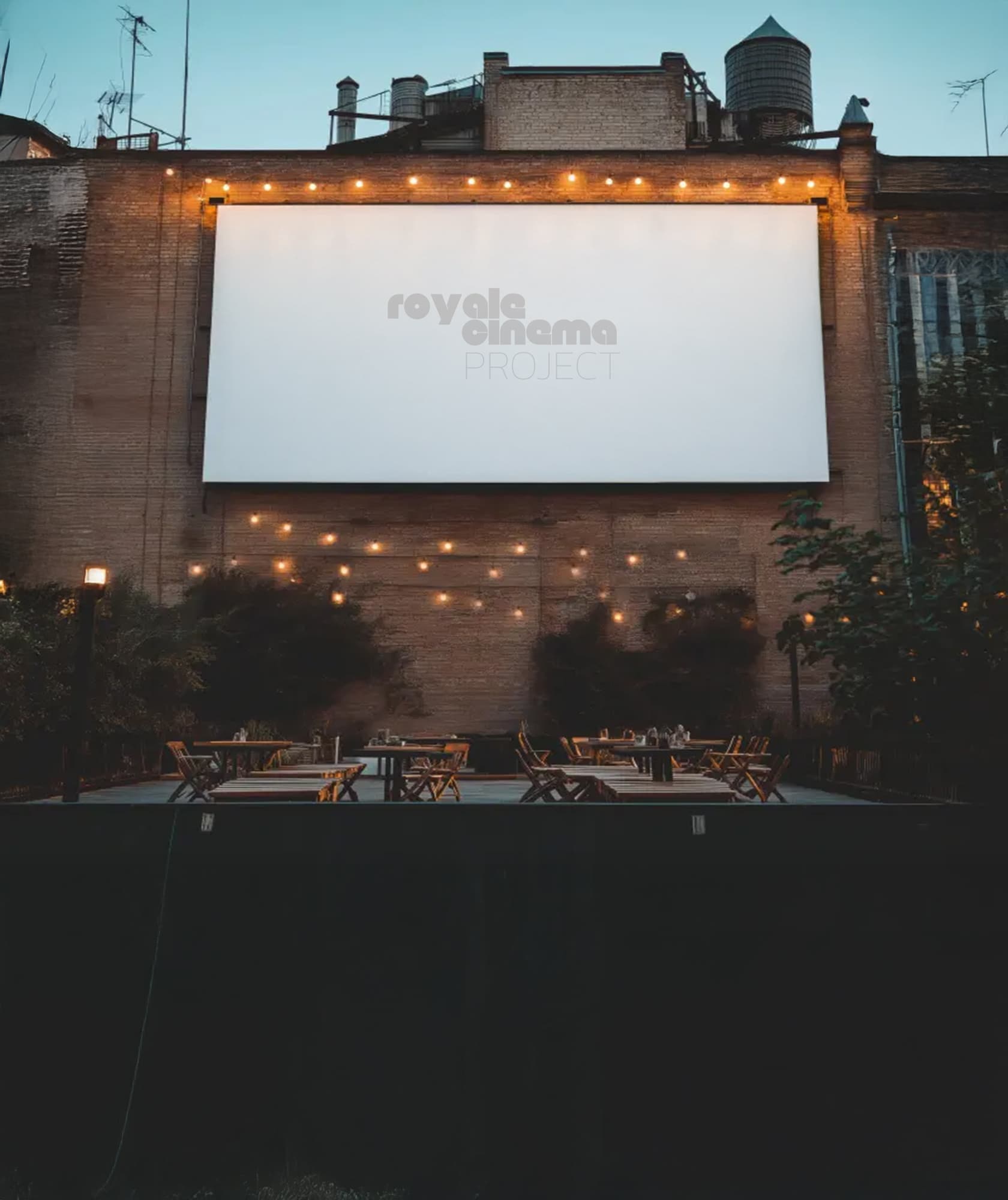 An outdoor movie screen with the Royale Cinema Project wordmark, under string lights